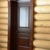 Входная дверь из массива лиственницы. Дверь декорирована *стаканами* и *розетками*. Установка доборов и наличников в проем бревенчатого дома требовала достаточно кропотливой работы с подгонкой бревен.